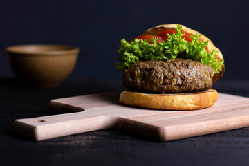 Big hamburger sandwich with lettuce and tomato on artisan bread. Tasty looking. Thick hamburger meat.