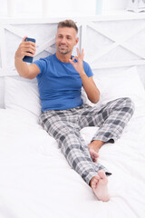 blogging man with phone wear pajama, ok. blogging man with phone in bed.