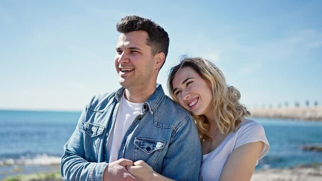Man and woman couple smiling confident hugging each other at seaside