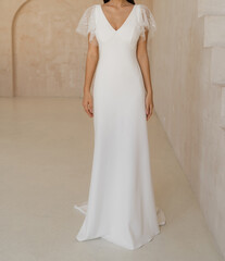 Gorgeous classic long wedding dress with cleavage and wide short sleeves decorated with floral lace. Bride in the white wedding dress with deep neckline