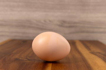 Farm fresh brown egg on a counter in the kitchen. Wood background.