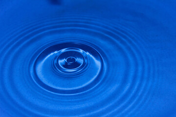 Water drops fall on the blue water surface