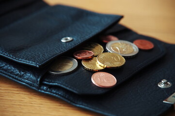 Euro coins in black wallet on wooden table