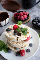 Rice cakes with berries and chocolate. Deliciously. A snack On a gray background