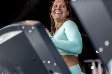 Fototapeta na wymiar Young athlete woman running on machine in gym