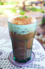 Glass of Iced Mint Cocoa Latte Isolated on Garden Table