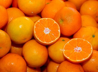 orange clementines or tangerines and some cut in half for sale in the greengrocer