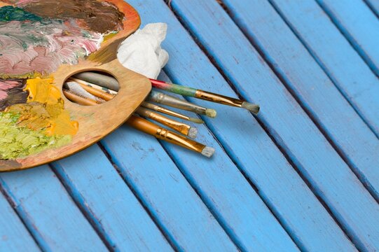 Row of artist colored paintbrushes with paints on background.