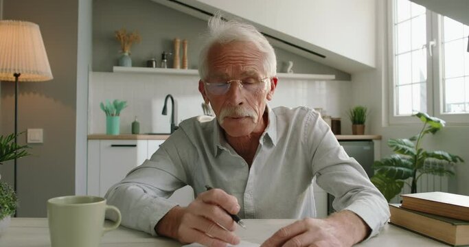 Webcam view of teacher, professor, elderly man writes in notebook. Male tutor conducts an individual online video chat lesson. Caucasian senior male teacher rehearses with student on online connection