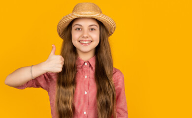 happy teen kid in straw hat on yellow background. thumb up