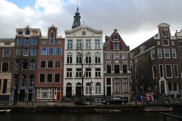 Obraz premium canal, river and old brick houses or flat buildings in amsterdam (the netherlands) 