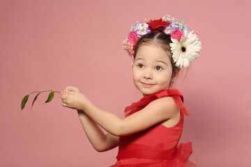 little girl in red dress with flowers in hair dress happy close up portrait on pink background