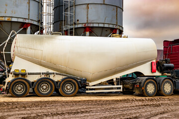 Large truck for transporting cement. A cement truck unloads cement at a concrete plant. Concrete...