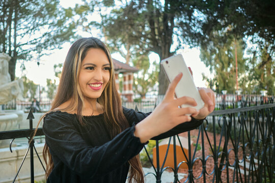 white-skinned latina woman in black clothes taking a selfie in the city of peace with a smile on her face.