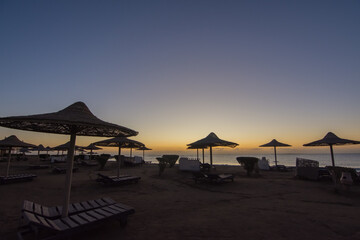 lot of umbrellas at the beach during colorful sunrise on vacation