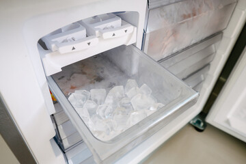 Ice maker in the refrigerator with some ice cubes