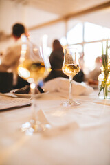 Two glasses of wine on a table in a restaurant backlit by the sun. 