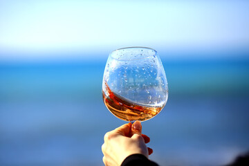 a glass of port wine on the background of the sea, a hand with wine