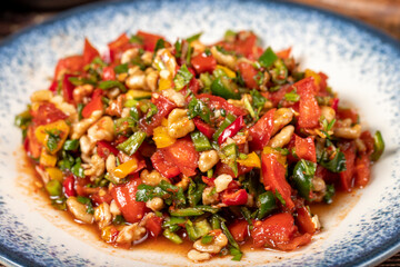 Gavurdagi salad. Walnut salad on wood background. Healthy salad prepared with tomatoes, peppers, cucumbers, onions, pomegranate syrup, olive oil and walnuts. Close up