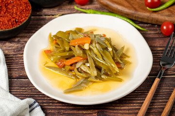 Green bean dish with olive oil on wood background.