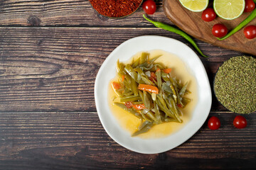 Green bean dish with olive oil on wood background. Top view. Empty space for text. Copy space
