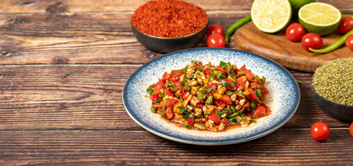 Gavurdagi salad. Walnut salad on wood background. Healthy salad prepared with tomatoes, peppers, cucumbers, onions, pomegranate syrup, olive oil and walnuts. Top view. Empty space for text. Copy space