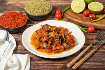 Eggplant dish with vegetables fried in olive oil on a wooden floor.