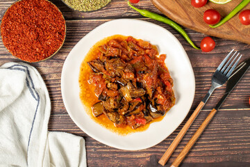 Eggplant dish with vegetables fried in olive oil on a wooden floor. Top view