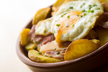 Fried eggs with chips and serrano ham. Traditional Spanish tapa nicknamed Huevos Rotos.