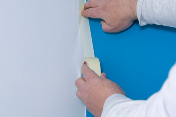 Applying masking tape  to be painted. Border of white and blue on the walls