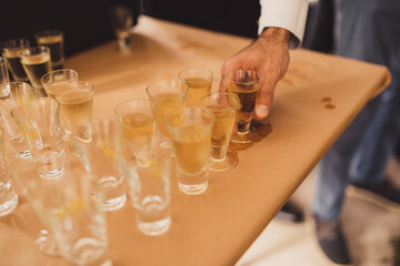 Hand taking a glass of liquor from a table.