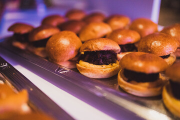 Mini burgers on a silver tray.