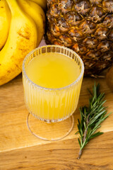 a glass of pineapple juice and a pineapple on wooden tray