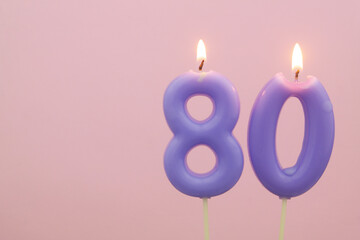 Colorful birthday candles burning and melting on pink background, numbers 80. Copy space for text.