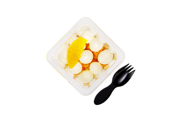 Dessert of cream, jam and orange in a plastic glass on a white background.