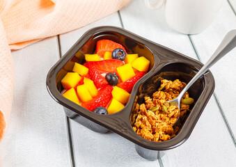 Dessert of cream, mango, strawberries and muesli on a wooden background.