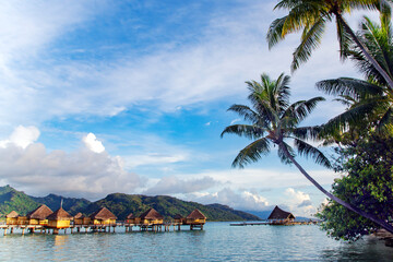 Overwater bungalows stretching out across the lagoon and a few catamarans in a quiet bay in Bora...