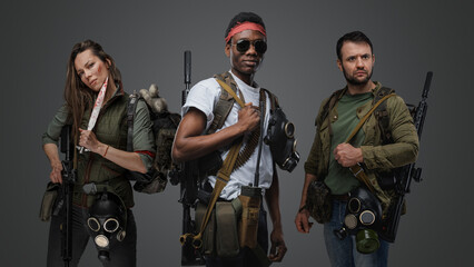 Portrait of multiethnic group of three people in post apocalyptic setting against gray background.