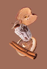 dried fruits - apple, persimmon, orange, cinnamon on a brown background, flying food