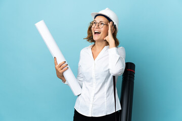 Young architect Georgian woman with helmet and holding blueprints over isolated background smiling a lot