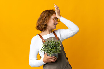 Young Georgian woman holding a plant isolated on yellow background has realized something and intending the solution