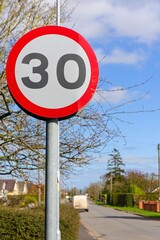 UK speed limit sign with a road soft-focused in the background
