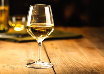 Wineglass of white wine on a wooden table in a restaurant