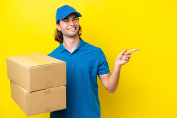 Delivery handsome man isolated on yellow background pointing finger to the side