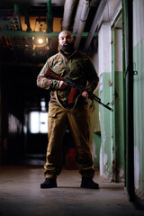 Portrait of the armed bearded man looking with a serious face straight at the camera
