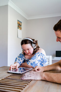 Teen girl with down syndrome listening to music on tablet with headphones