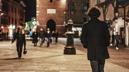 Anonymous Young Man Walking Alone in City Square at Night