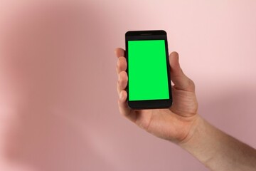Person holding a phone with a green screen