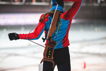 Biathlete with rifle on a shooting range during biathlon training, skiers on training ground in winter snow, athletes participate in biathlon competition on slope piste