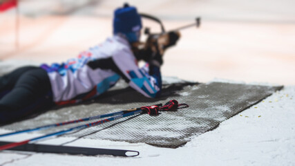 Biathlete with rifle on a shooting range during biathlon training, skiers on training ground in winter snow, athletes participate in biathlon competition on slope piste